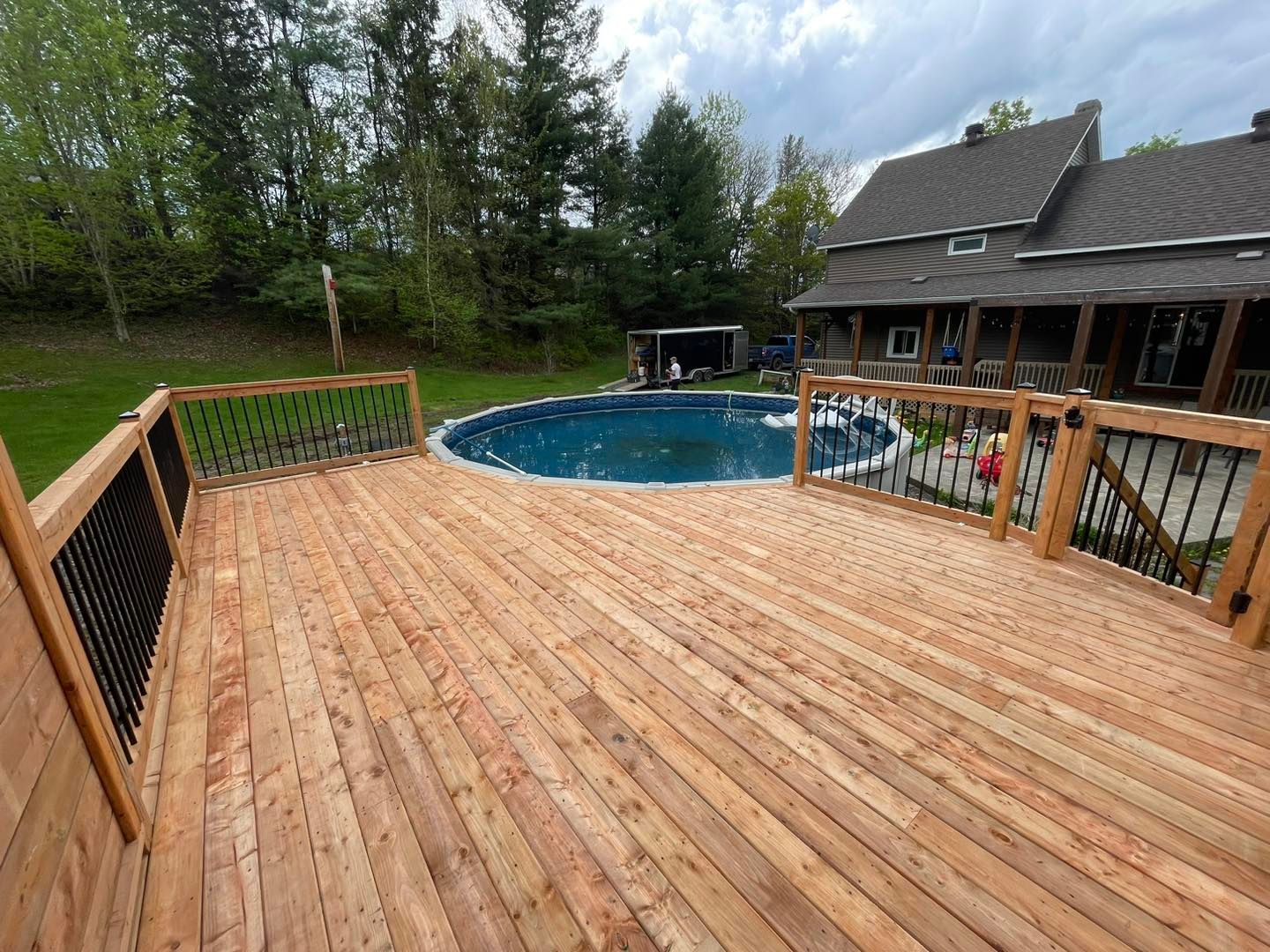 Une grande terrasse en bois avec une piscine en arrière-plan.