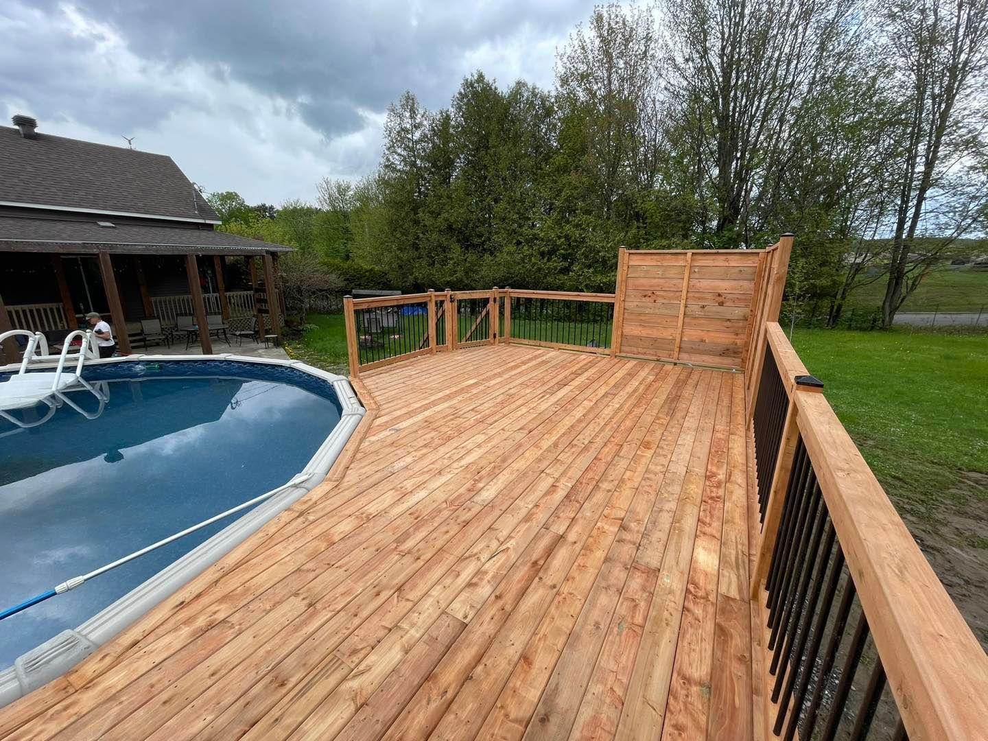Une terrasse en bois avec une piscine en arrière-plan.