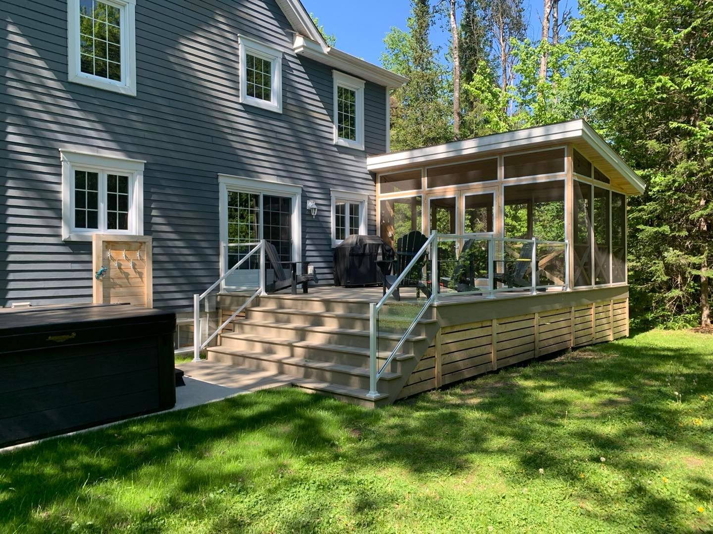 Une maison avec un porche grillagé et un bain à remous dans l'arrière-cour.