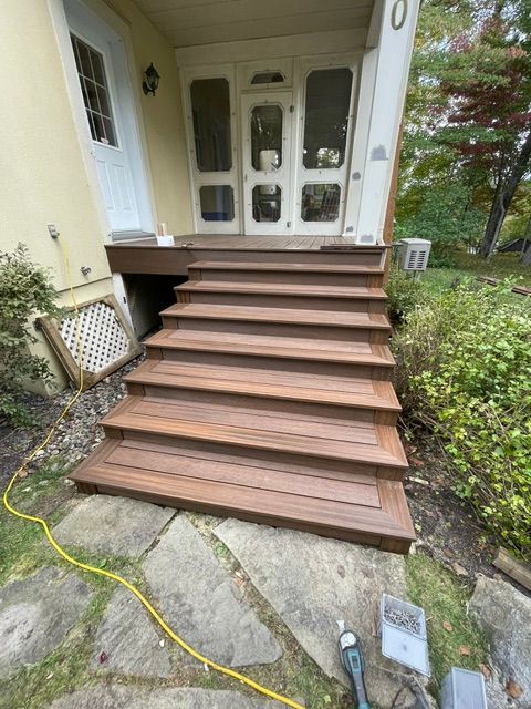 Une terrasse en bois avec des escaliers menant à la porte d'entrée d'une maison.