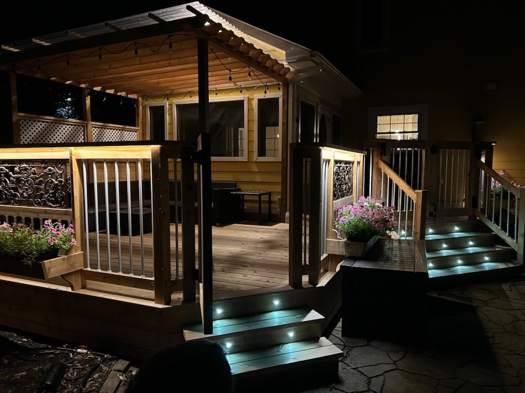 Une terrasse avec des escaliers qui y mènent est éclairée la nuit.