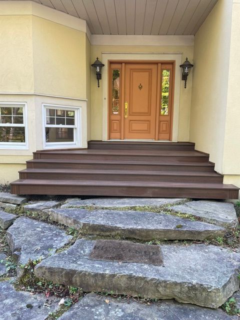 Une maison jaune avec une porte en bois et des marches en pierre