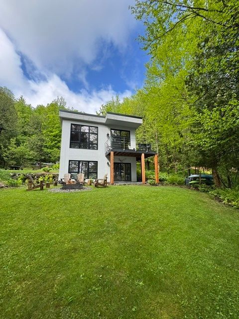 Une maison blanche avec une grande pelouse devant elle entourée d'arbres.