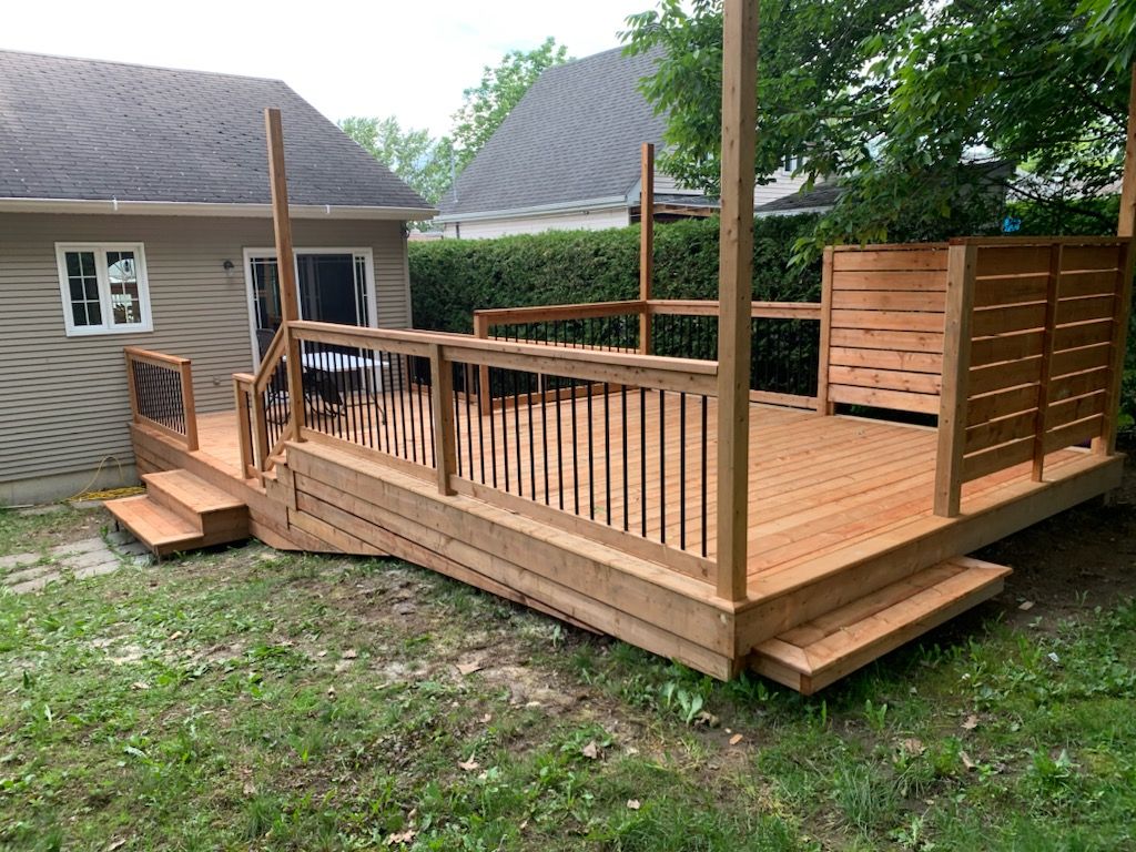 Une terrasse en bois avec des escaliers se trouve dans l'arrière-cour d'une maison.