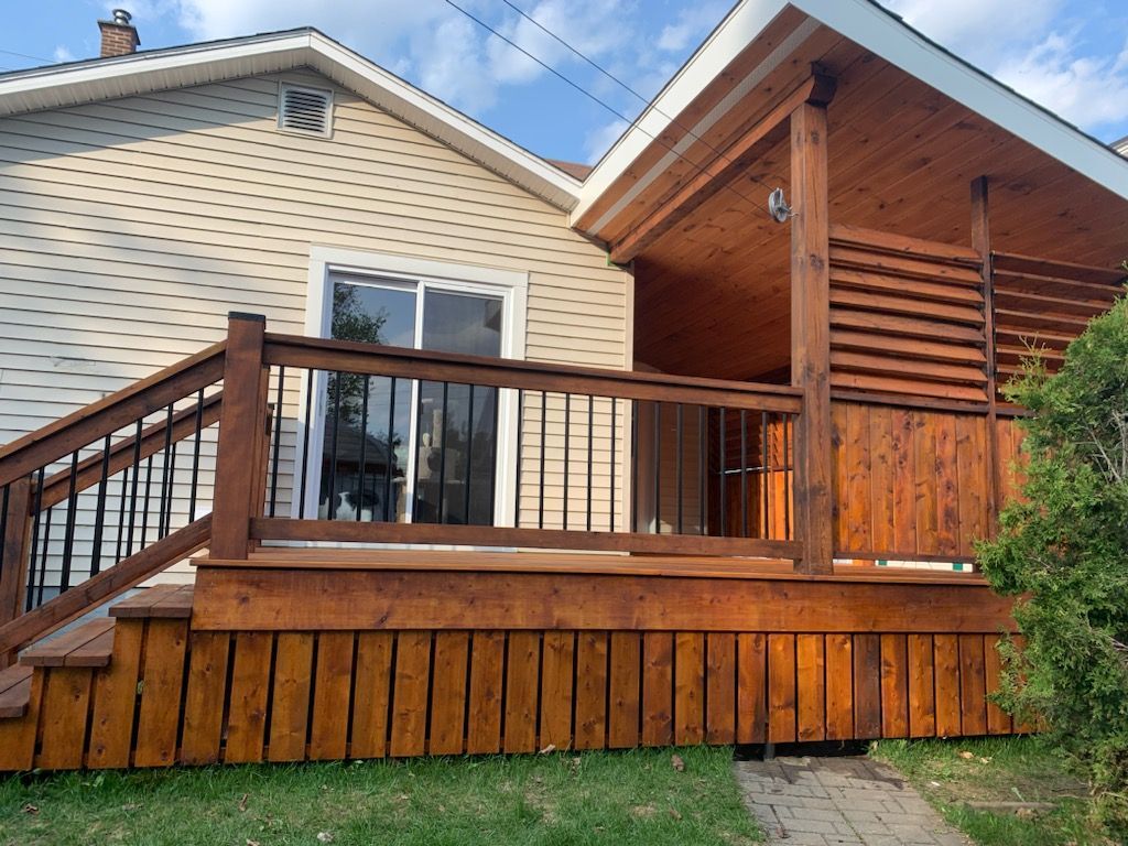 Une maison avec une terrasse en bois et des escaliers qui y mènent.
