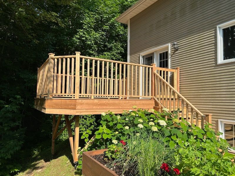 Une terrasse en bois est posée au sommet d'une colline à côté d'une maison.