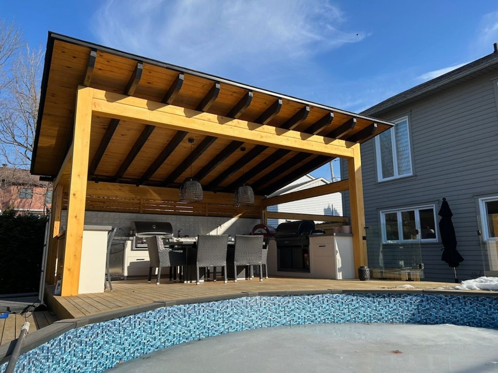 Un patio en bois avec un espace couvert et une piscine en arrière plan.