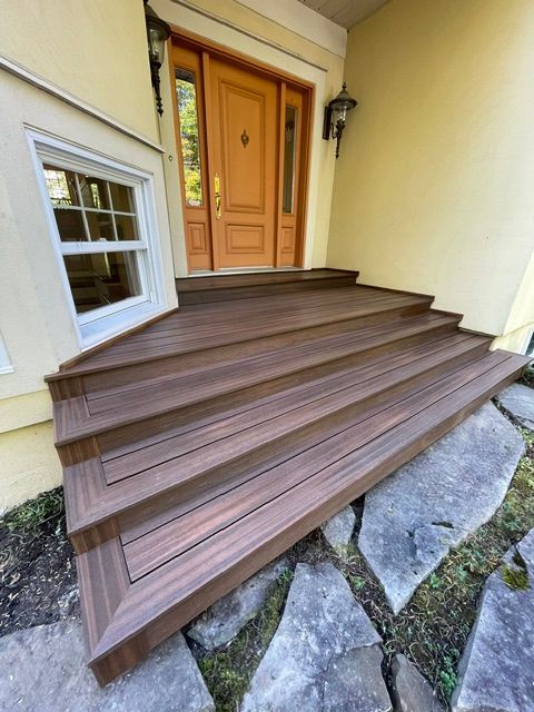 Un porche en bois avec des escaliers menant à la porte d'entrée d'une maison