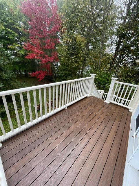 Une terrasse en bois avec une balustrade blanche et des arbres en arrière-plan.