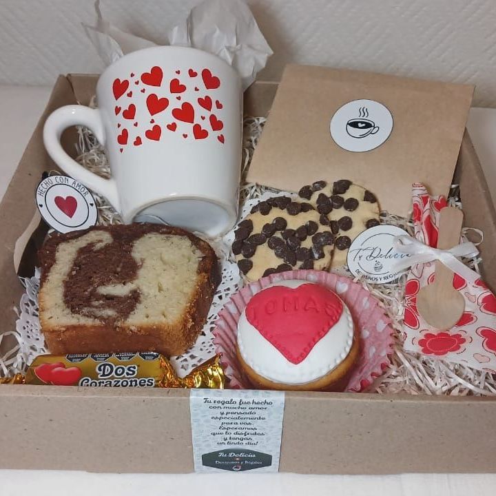 Una caja llena de una variedad de postres y una taza con corazones.