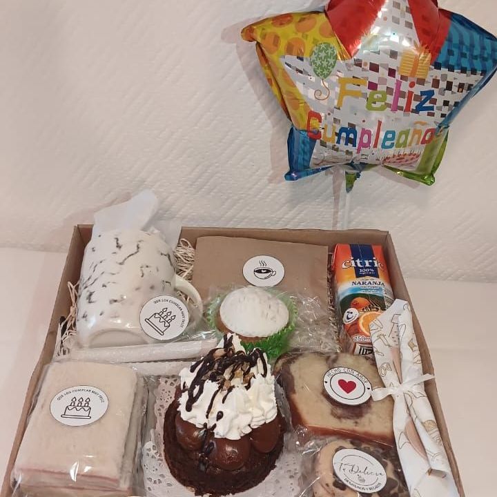 Una caja llena de comida y un globo sobre una mesa.