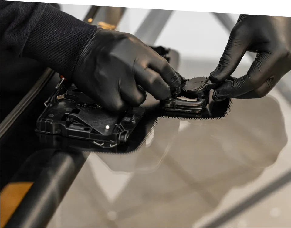 Electrician inspecting electrical panel, holding tablet, wearing hard hat and safety glasses.