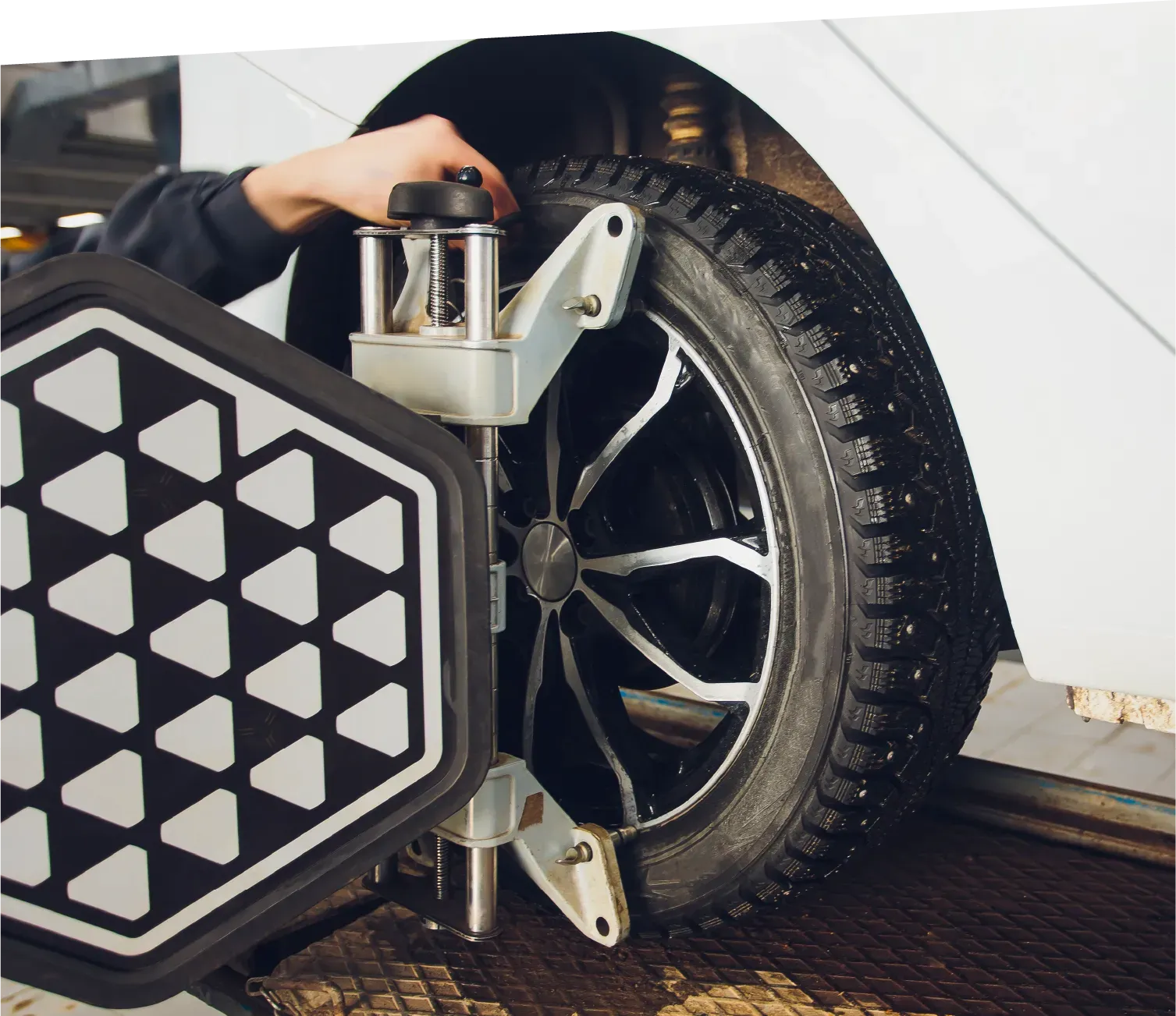 Gloved hand holding an orange and black multimeter with red and black probes, in front of a gray surface.