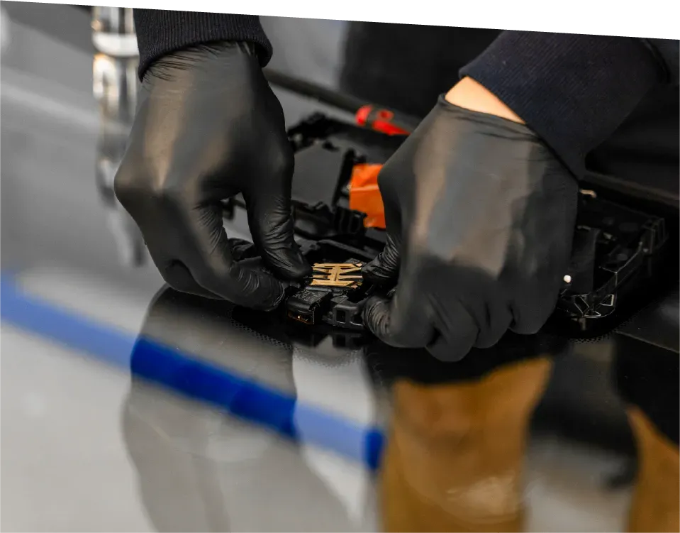 Hands of an electrician wiring a light switch, with visible colored wires and a wall outlet box.