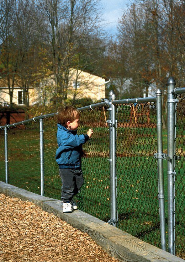 Little boy looking through chain link fence