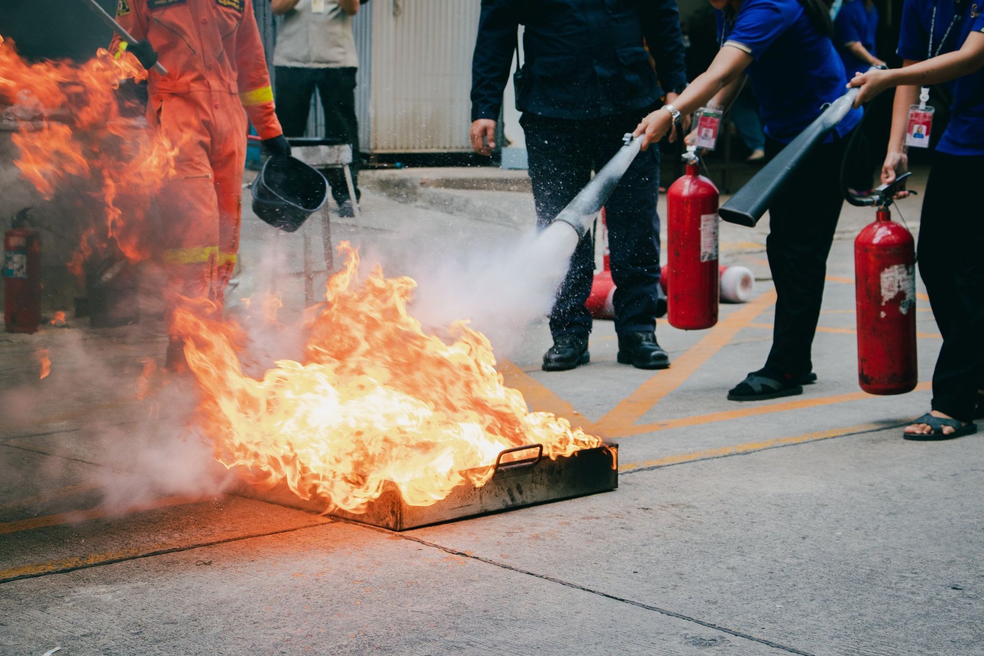 A group of people are using fire extinguishers to put out a fire.