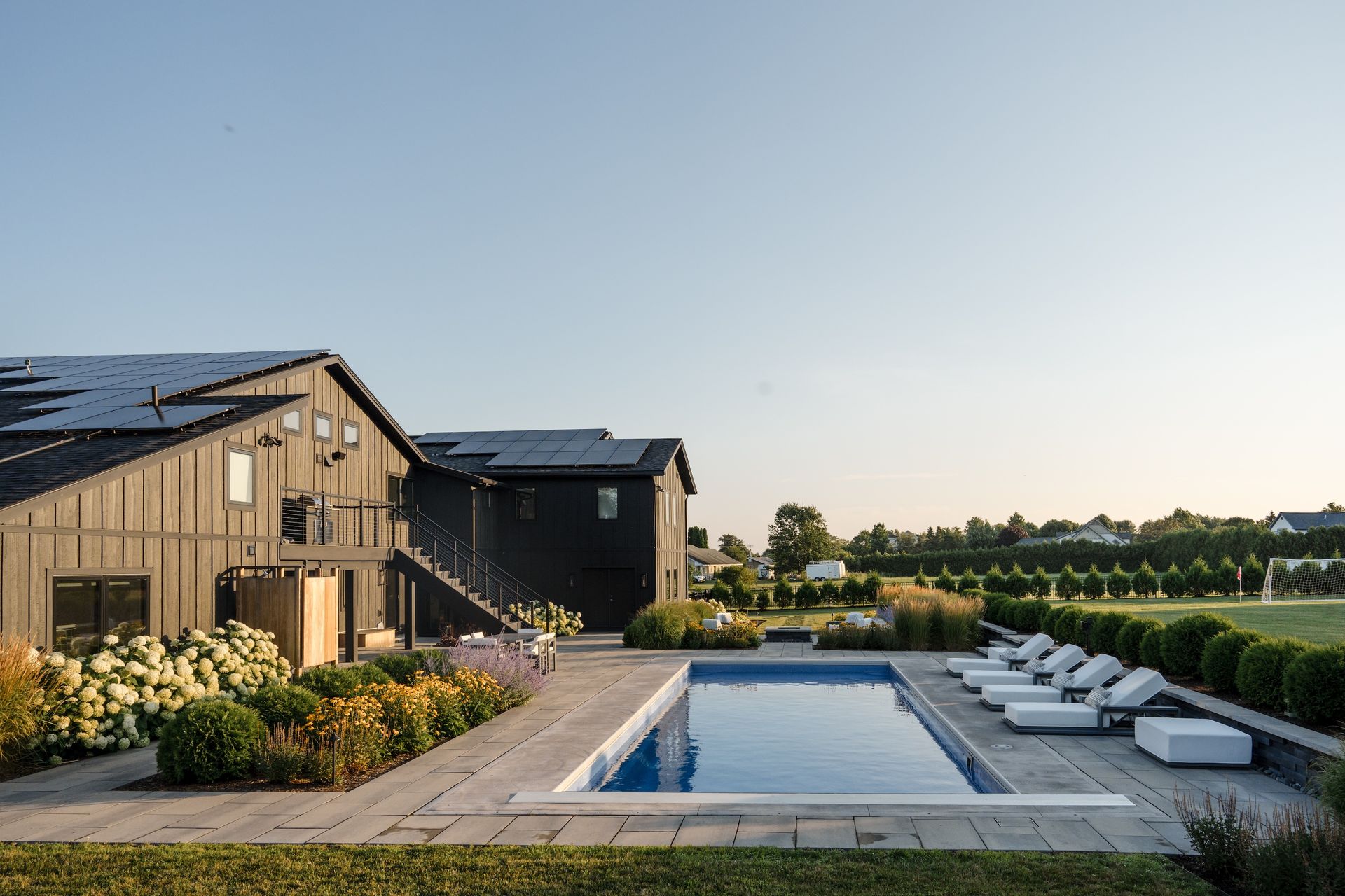 Overhead view of a rectangular fiberglass swimming pool with paved patio and lounge chairs. 