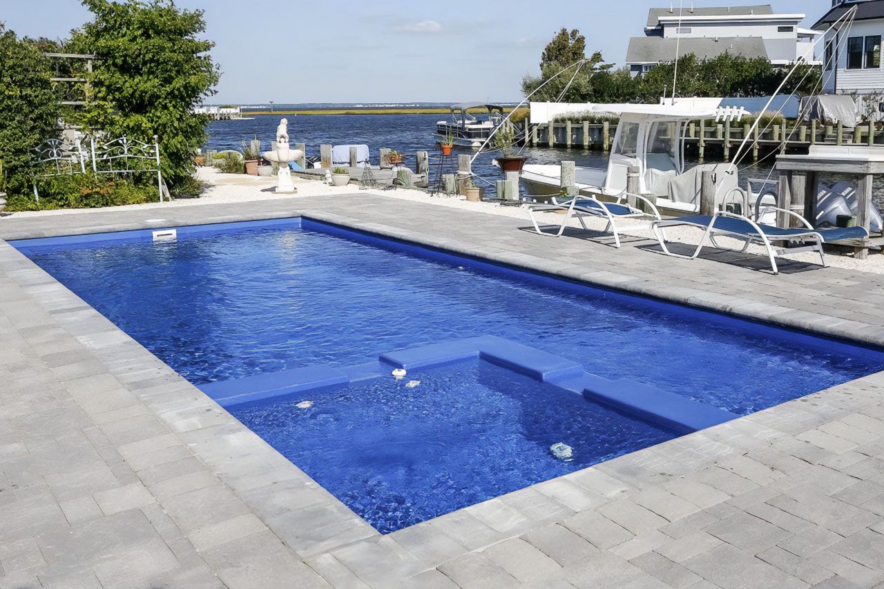 Fiberglass Swimming pool with blue water Bullnose concrete pavers around pool