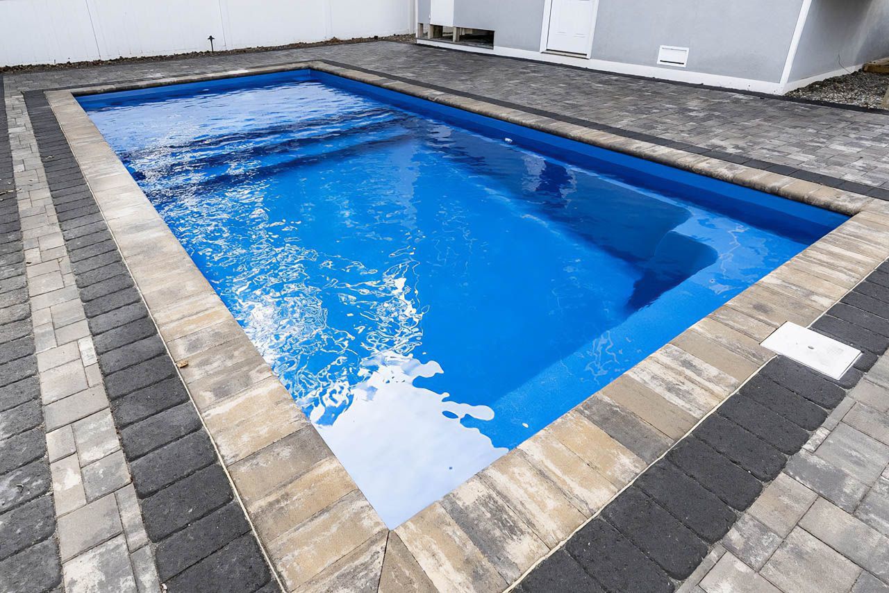 Fiberglass Swimming pool with blue water Bullnose concrete pavers around pool