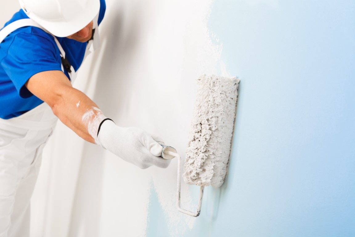 man painting interior walls white with a short handle paint roller