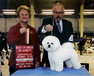 A man and woman holding a sign that says best of breed or variety
