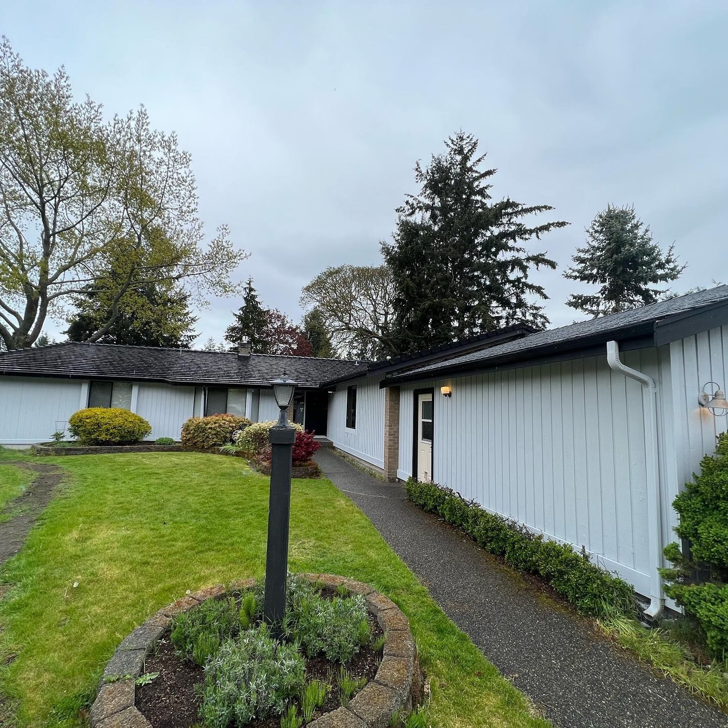 White mid-century modern home with a path leading to the front door, cloudy sky.