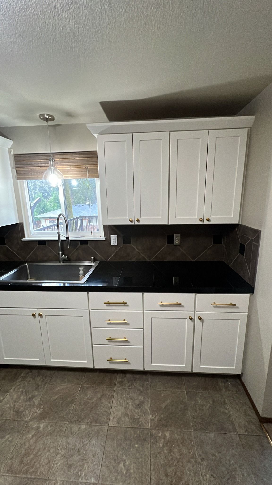 White kitchen cabinets, black countertops, and a dark backsplash.