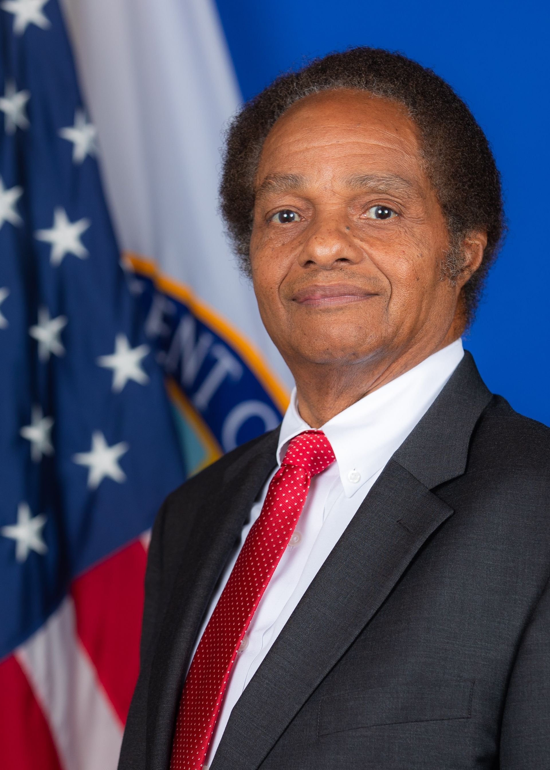 A woman is sitting at a desk with a laptop and a vase of flowers.