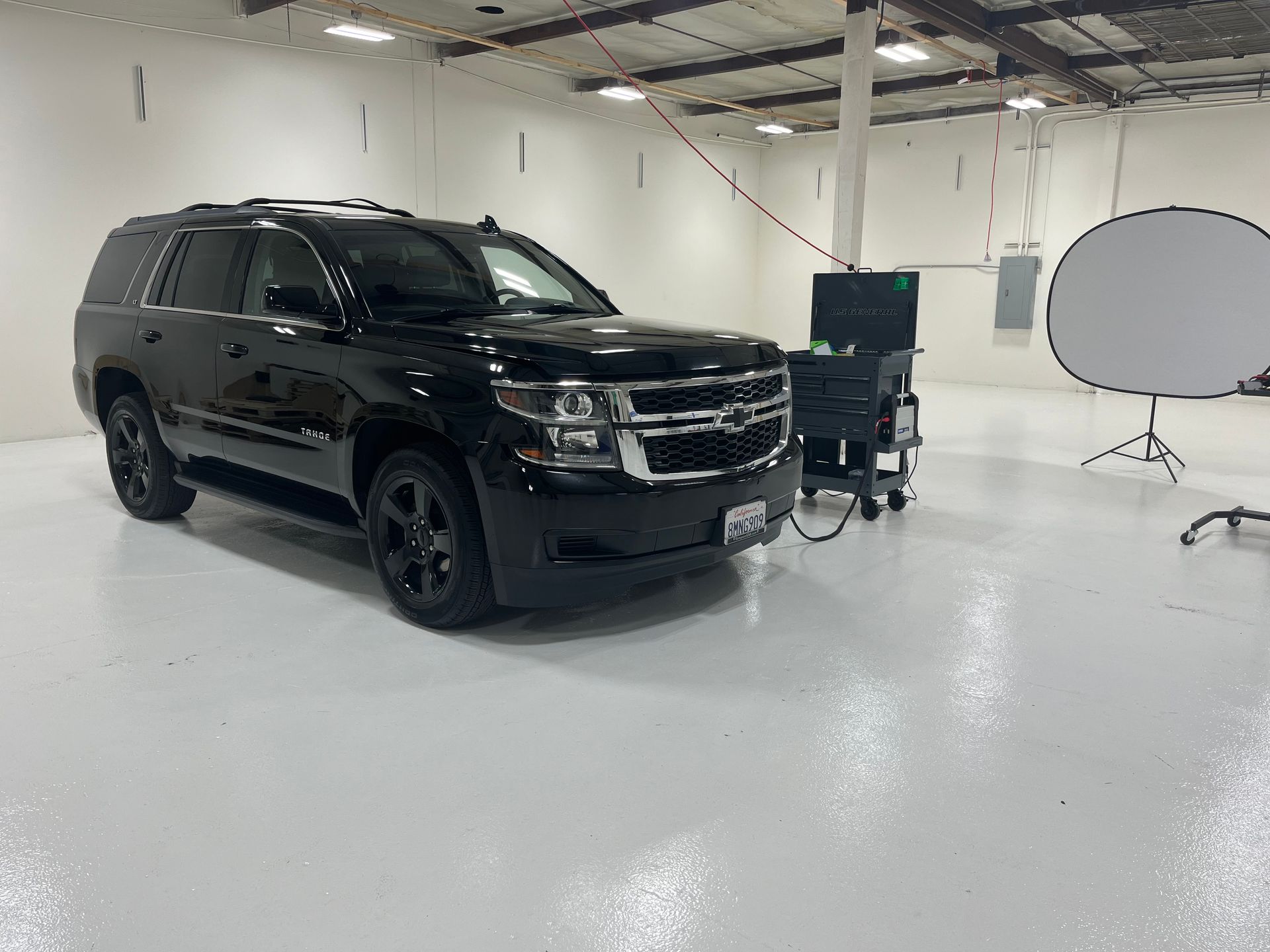 A black suv is parked in a warehouse with a white floor.