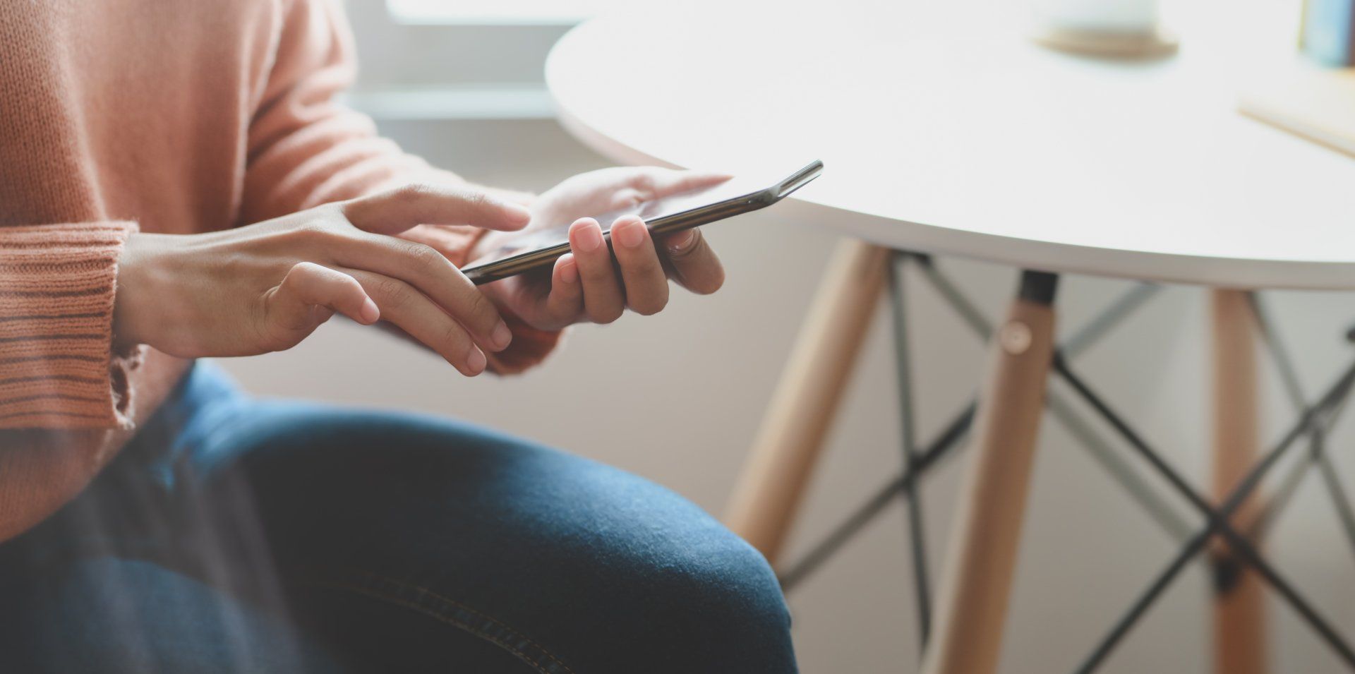 A woman is sitting at a table using a cell phone.