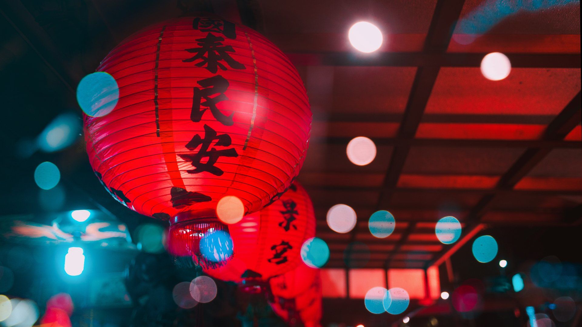 Photo by Andrew Haimerl A row of red lanterns hanging from the ceiling of a building.
