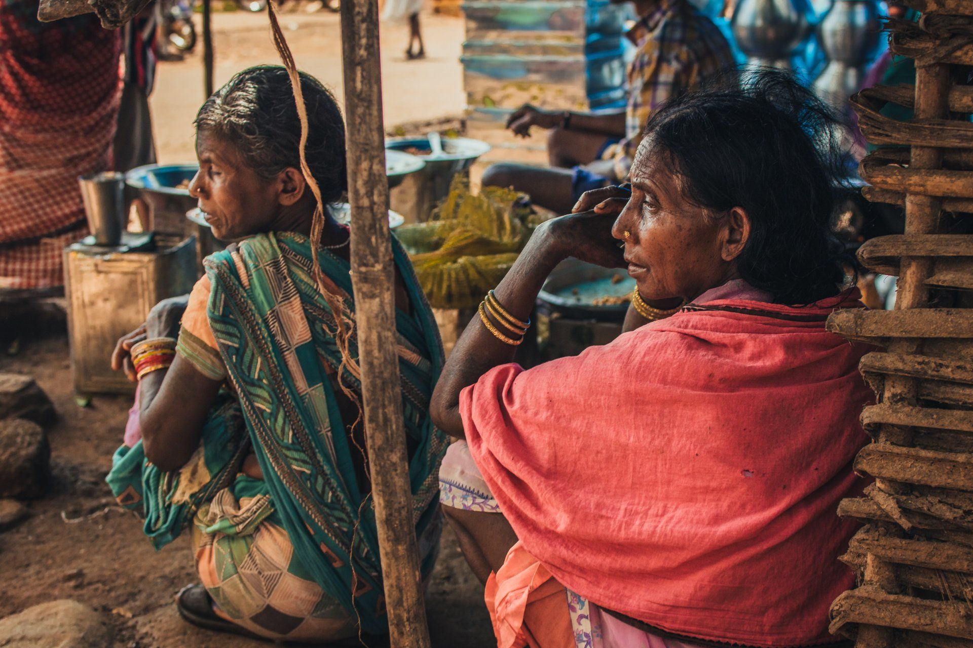Photo by Parij Borgohain Two women are sitting next to each other on the ground.