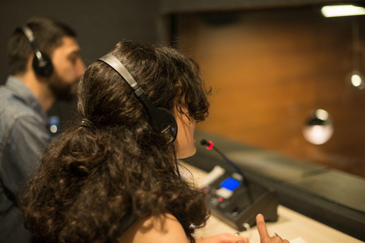 A woman wearing headphones is sitting in front of a microphone.