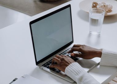 A woman is typing on a laptop computer at a desk.
