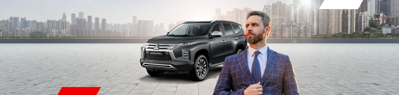 Um SUV preto com um homem de terno posando na frente. Prédios da cidade ao fundo.