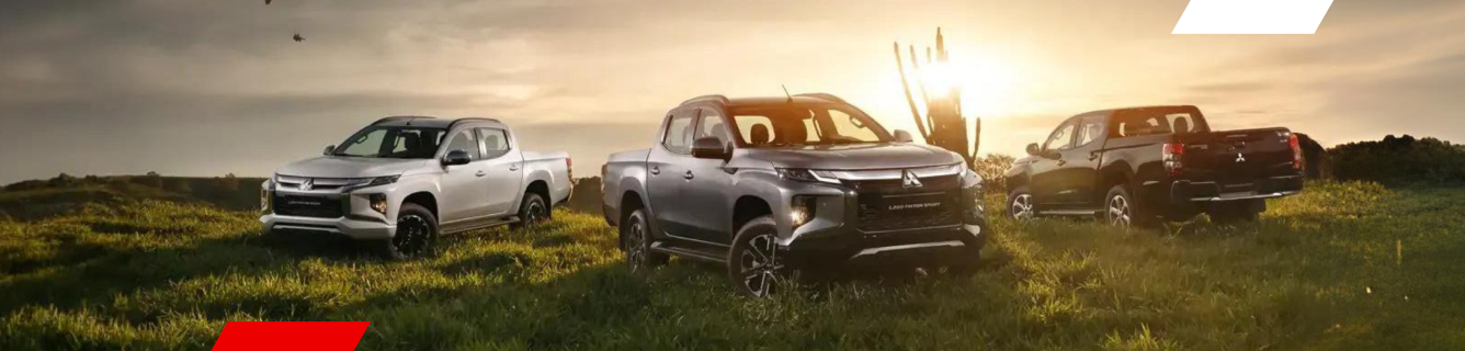 Três caminhonetes em um campo gramado com o pôr do sol ao fundo.