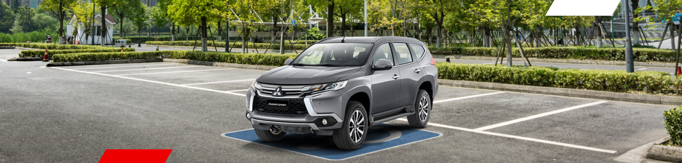 Um SUV cinza está estacionado em uma vaga reservada para deficientes em um estacionamento pavimentado e arborizado.