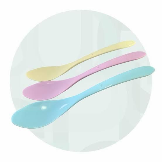 Tre cucchiai di plastica color pastello su uno sfondo circolare chiaro