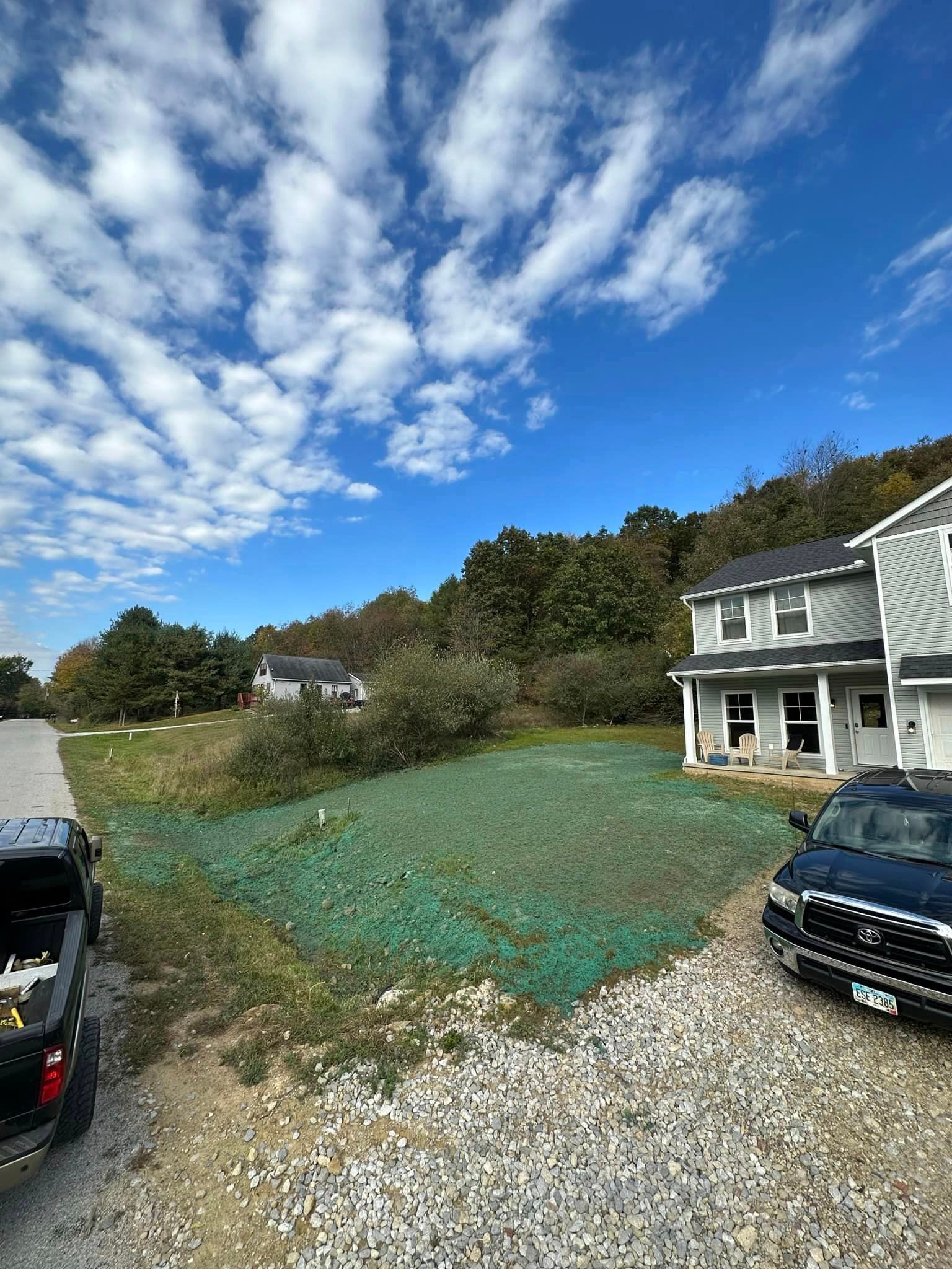A truck is parked in front of a house on a gravel road.