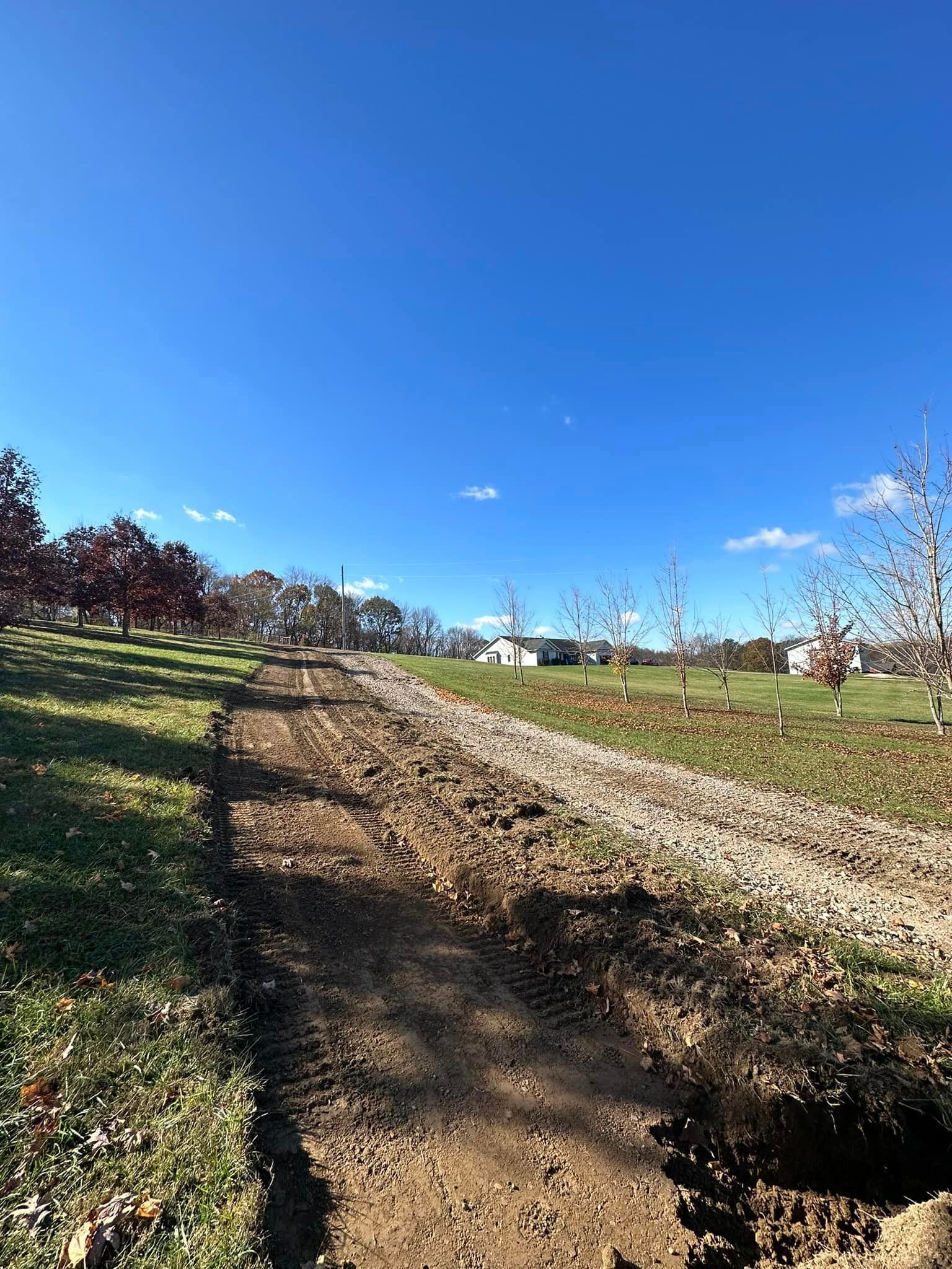 A dirt road going through a grassy field on a sunny day.