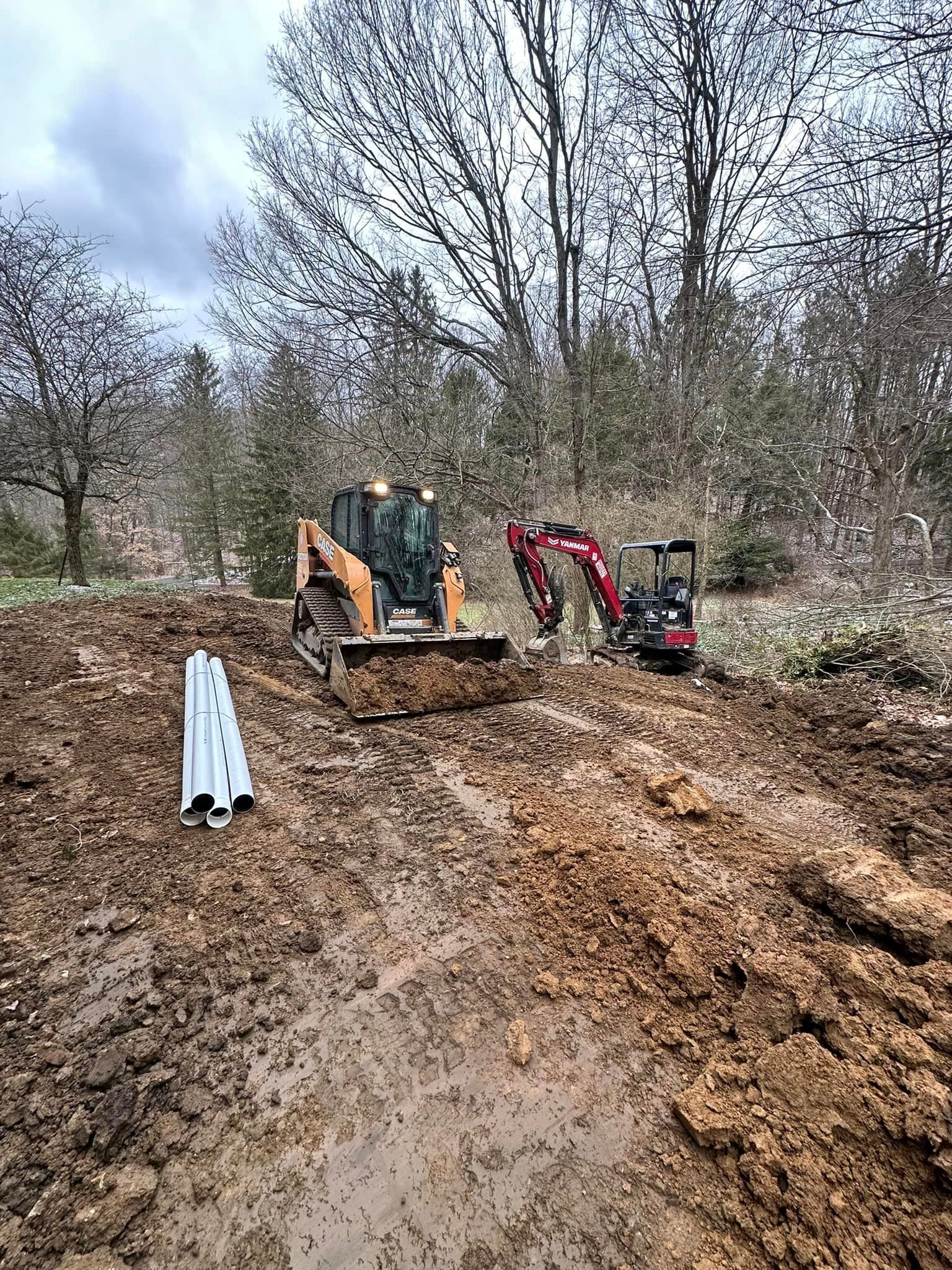 a bulldozer and an excavator are working in a muddy field .