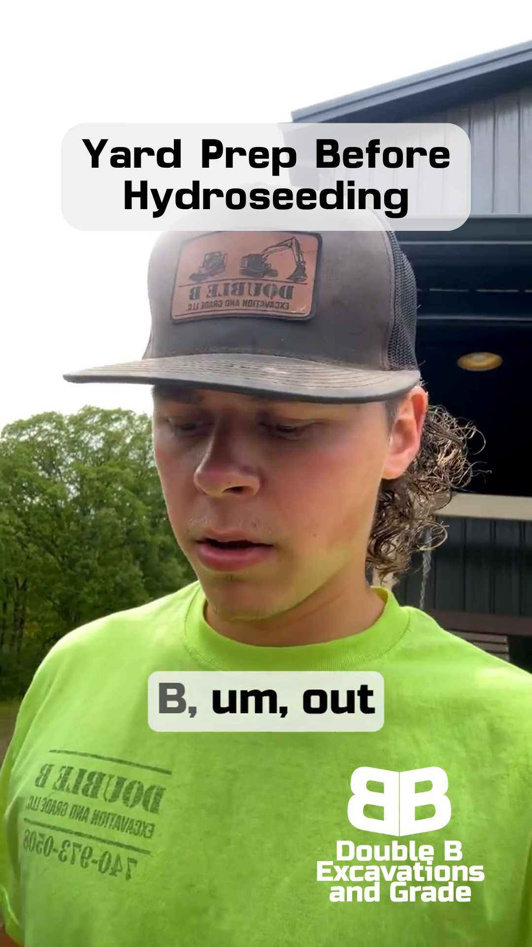 A young man wearing a hat and a green shirt is standing in front of a building.