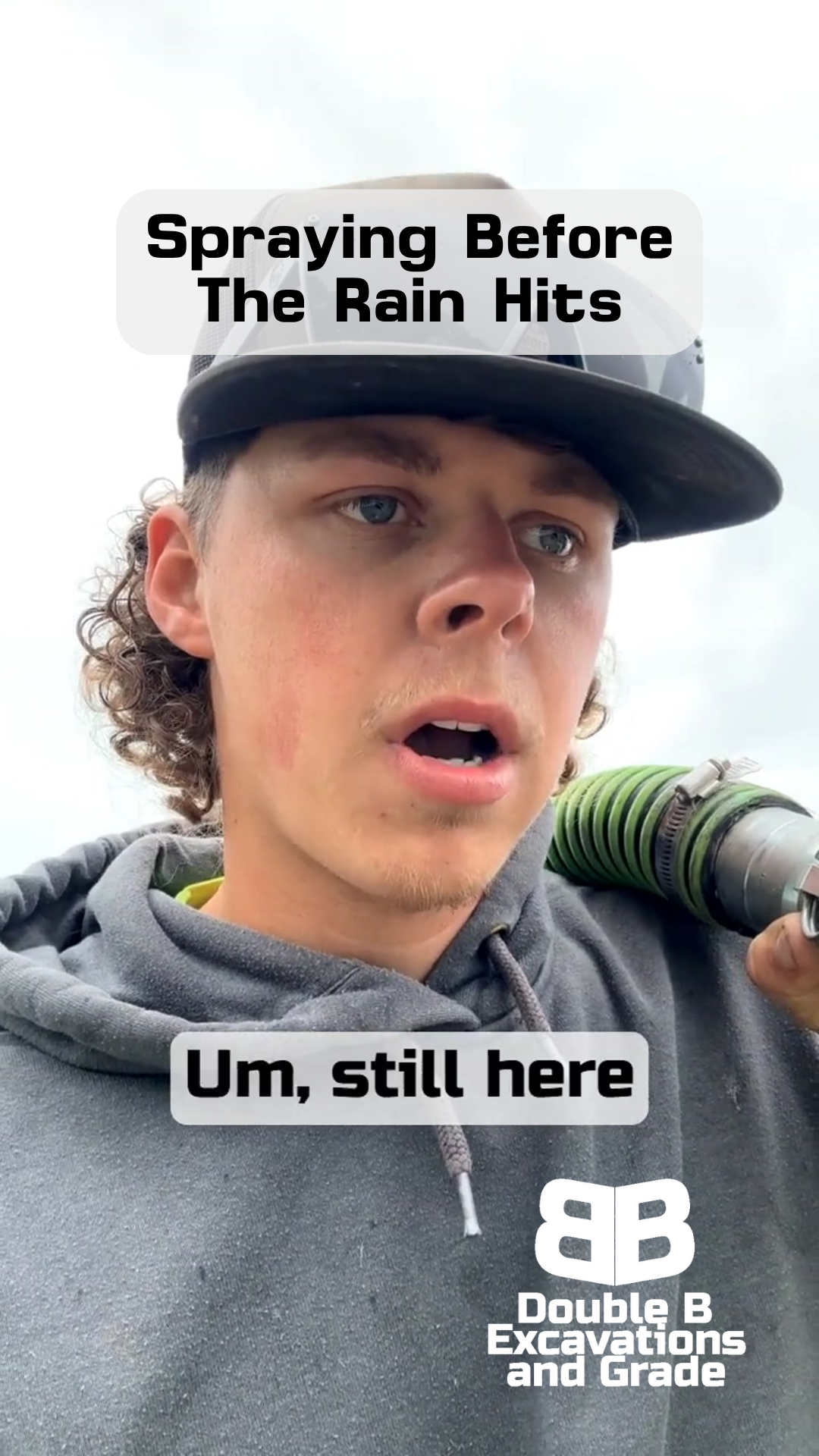 A man wearing a hat and a hoodie is spraying before the rain hits.