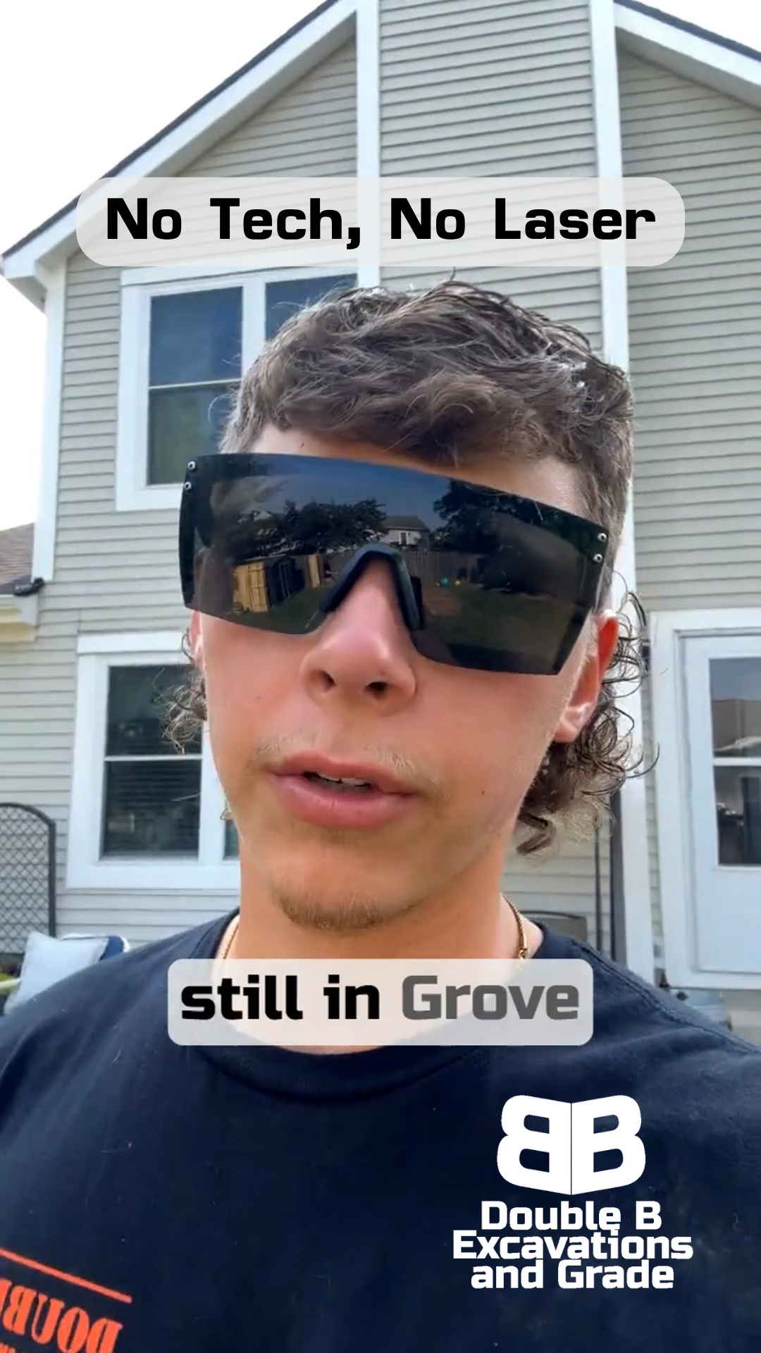 A man wearing sunglasses is standing in front of a house.