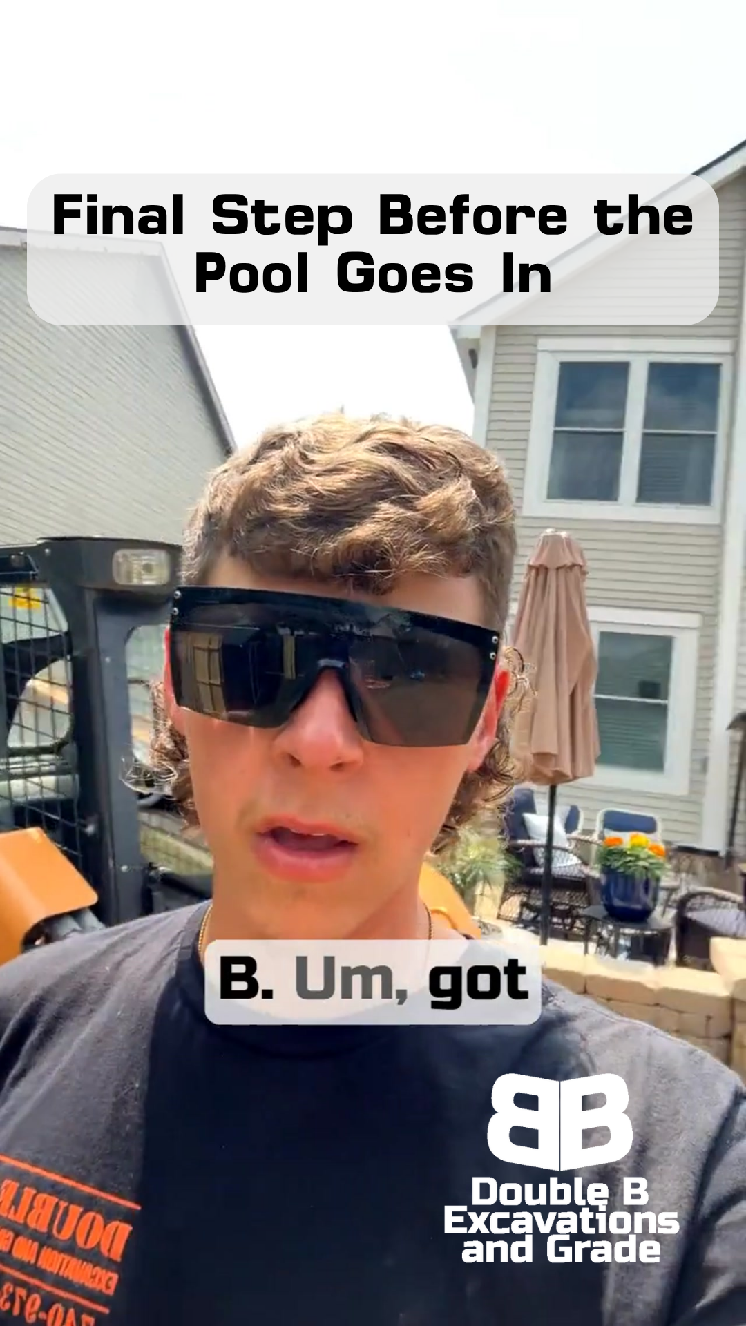 A man wearing sunglasses and a black shirt is standing in front of a house.