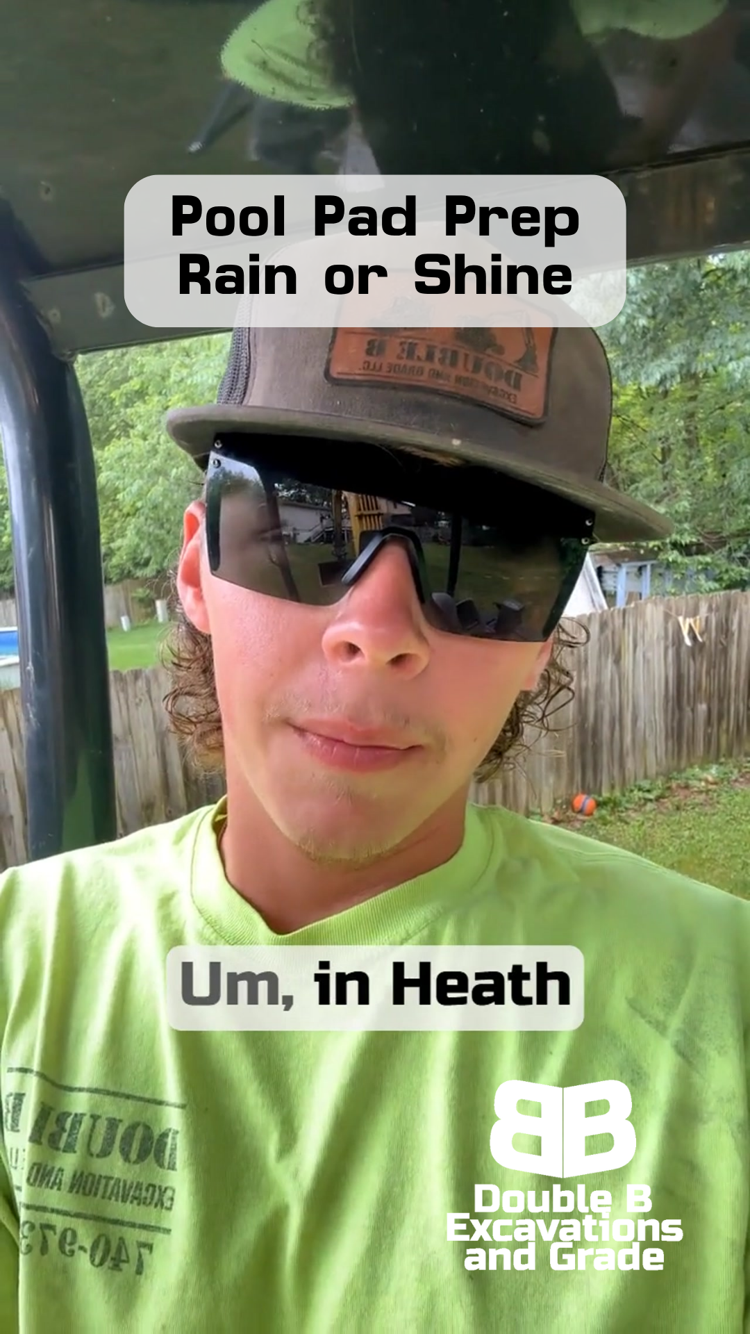 A man wearing sunglasses and a hat is standing in front of a fence.