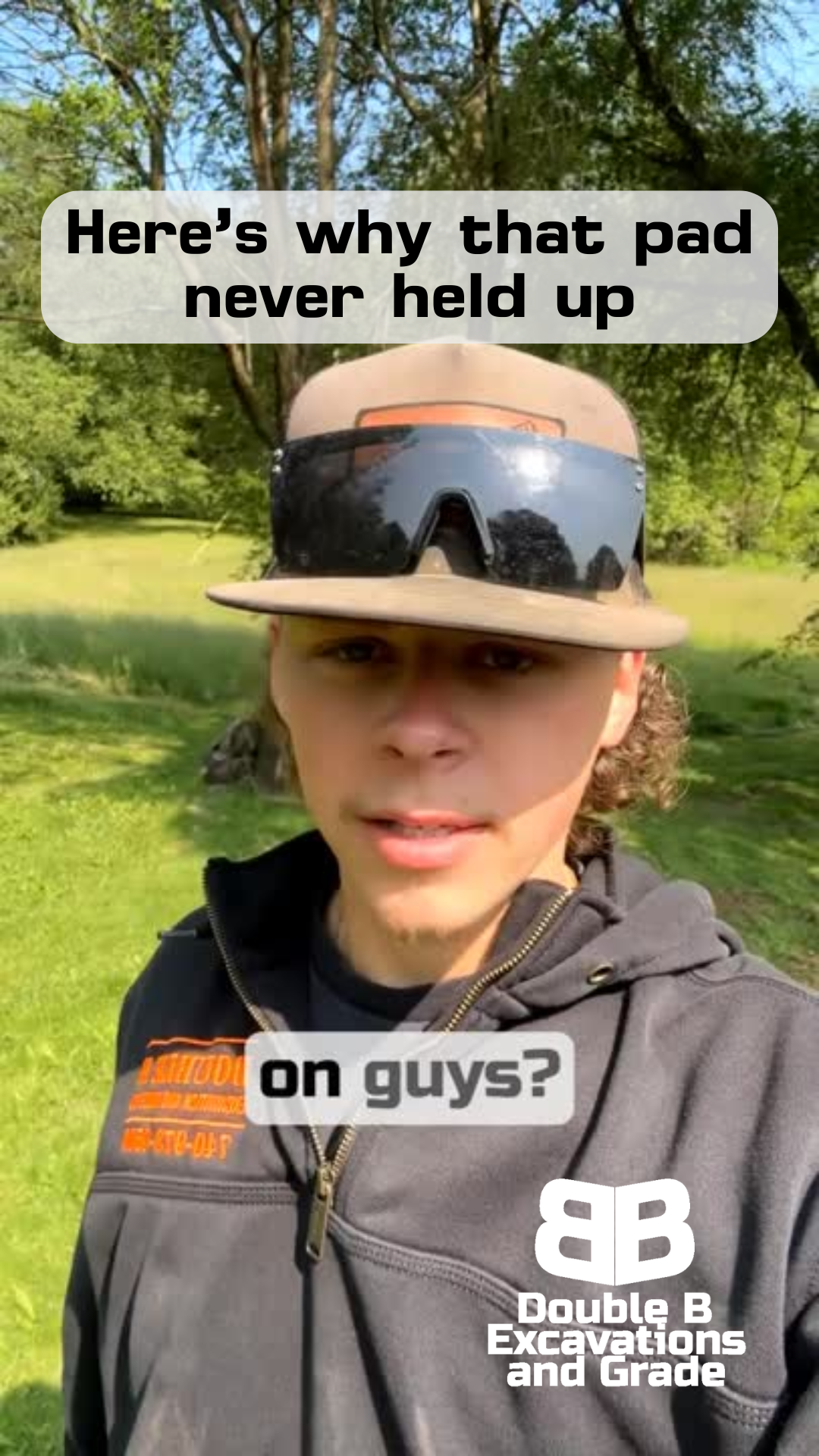 A man wearing a hat and sunglasses is standing in a field.