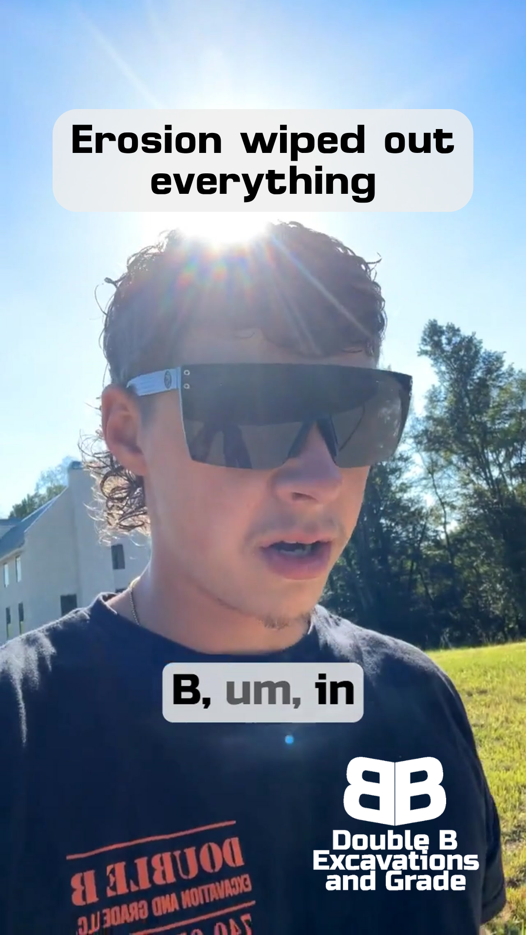 A man wearing sunglasses and a black shirt is standing in a field.