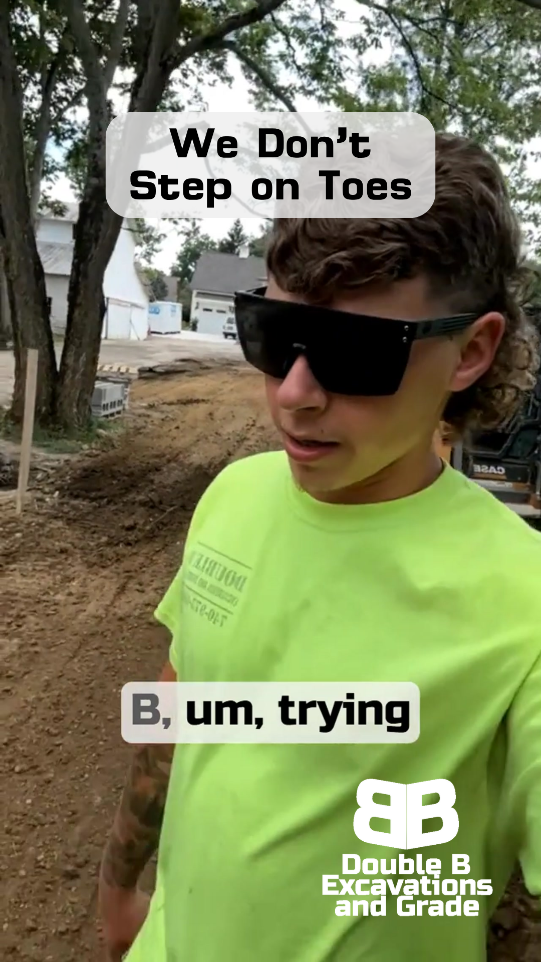 A man wearing sunglasses and a neon green shirt is standing in a dirt field.