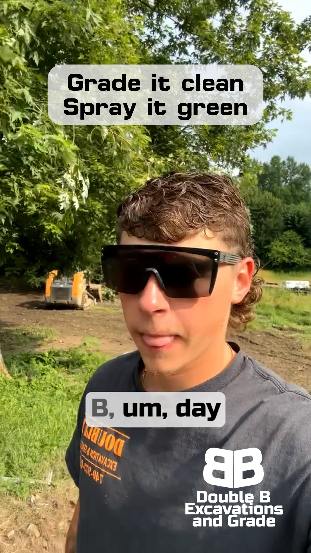 A man wearing sunglasses is standing in a field with a bulldozer in the background.